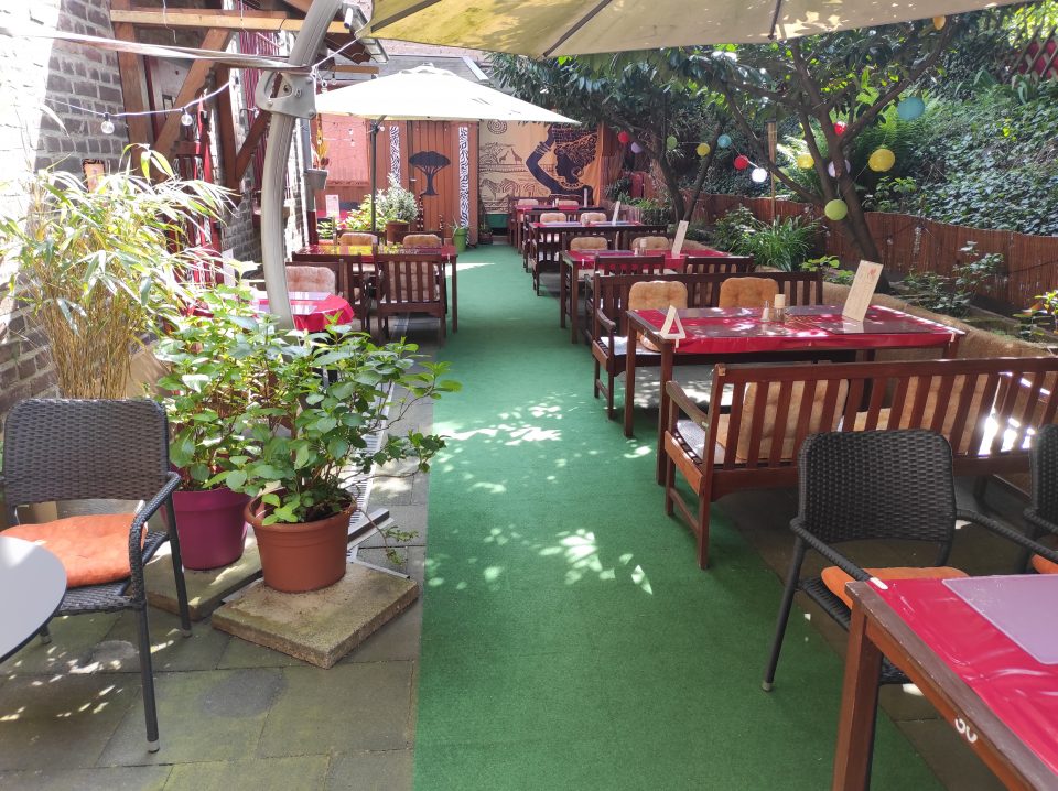 Sitzbänke unter Sonnenschirmen im begrünten Innenhof